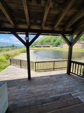 A wooden deck with a railing overlooking a body of water and greenery.