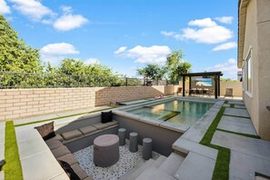 A backyard with a swimming pool, a covered seating area, and a patio with outdoor furniture. - Terra Sol Coachella | Saltwater Pool, Spa & Firepit (Coachella)