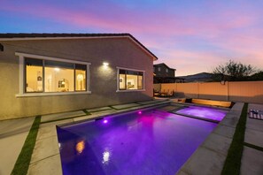 A residential backyard with a swimming pool, a house with large windows, and a wooden fence. - Terra Sol Coachella | Saltwater Pool, Spa & Firepit (Coachella)