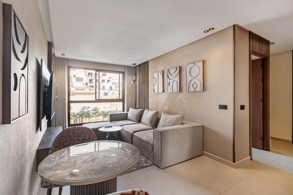 A modern living room with a sectional sofa, a round glass coffee table, and a TV mounted on the wall.