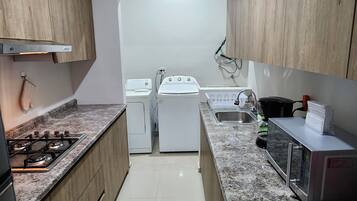 Una cocina con armarios de madera, una estufa a gas, un microondas y un lavamanos.