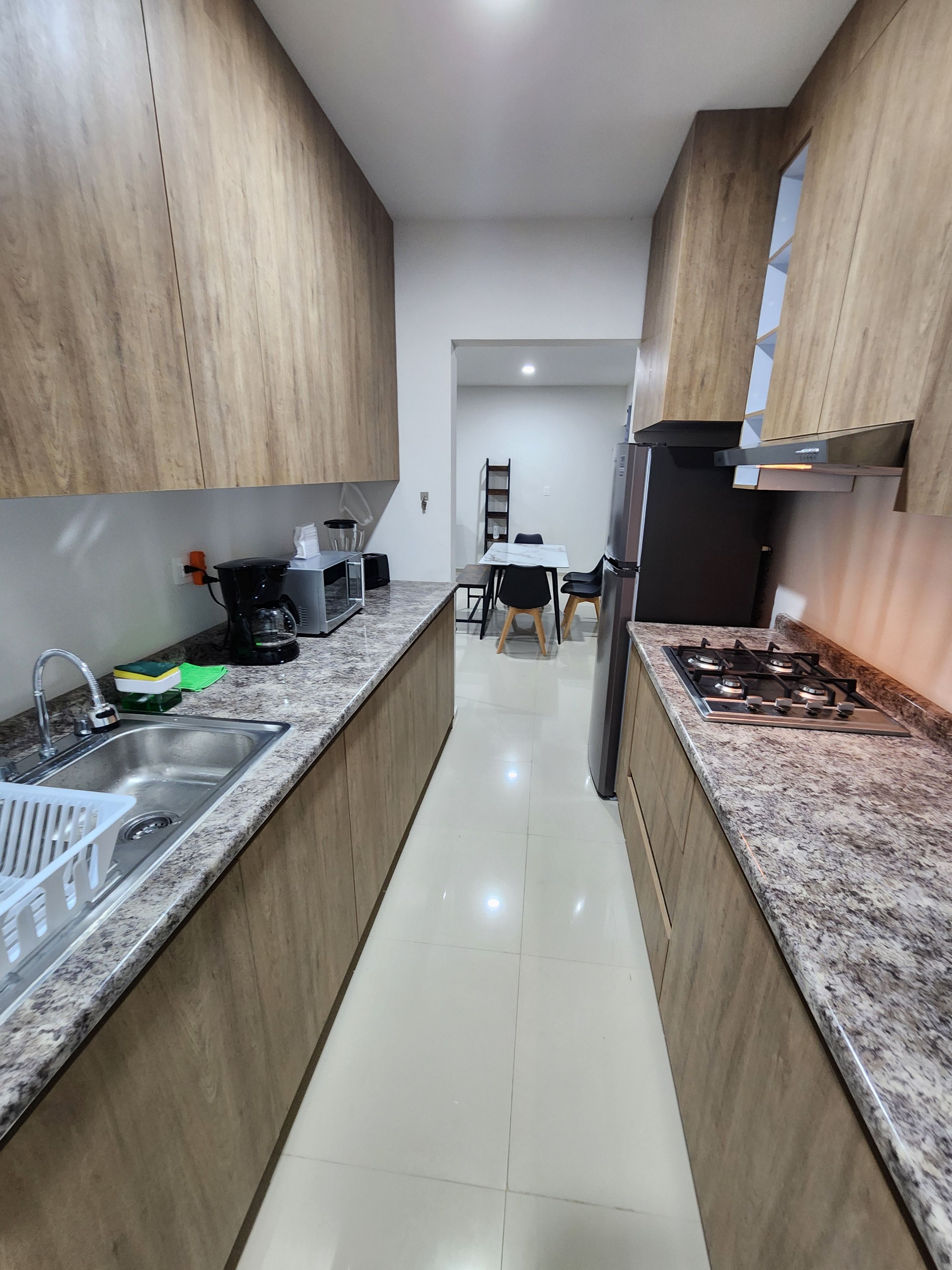 Cocina moderna con encimeras de granito, electrodomésticos de acero inoxidable y armarios de madera.