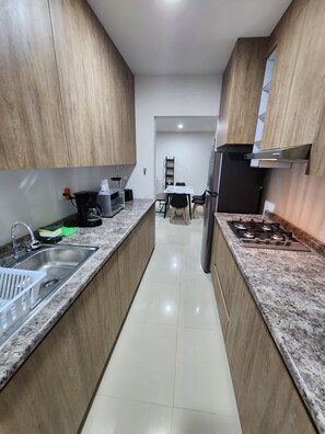 Cocina moderna con encimeras de granito, electrodomésticos de acero inoxidable y armarios de madera.