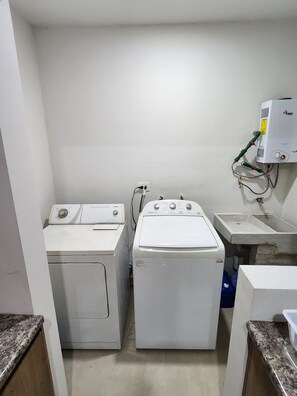 Une buanderie équipée de deux machines à laver à chargement frontal et d’un chauffe-eau.