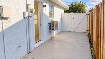 Il s’agit d’une propriété résidentielle dotée d’une terrasse en béton, d’un mur extérieur peint en blanc et d’une clôture en bois.