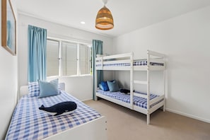 A room with a bunk bed, a single bed, and a hanging light fixture. - 180° Ocean Views | Steps to Sunrise Beach (Sunrise Beach)