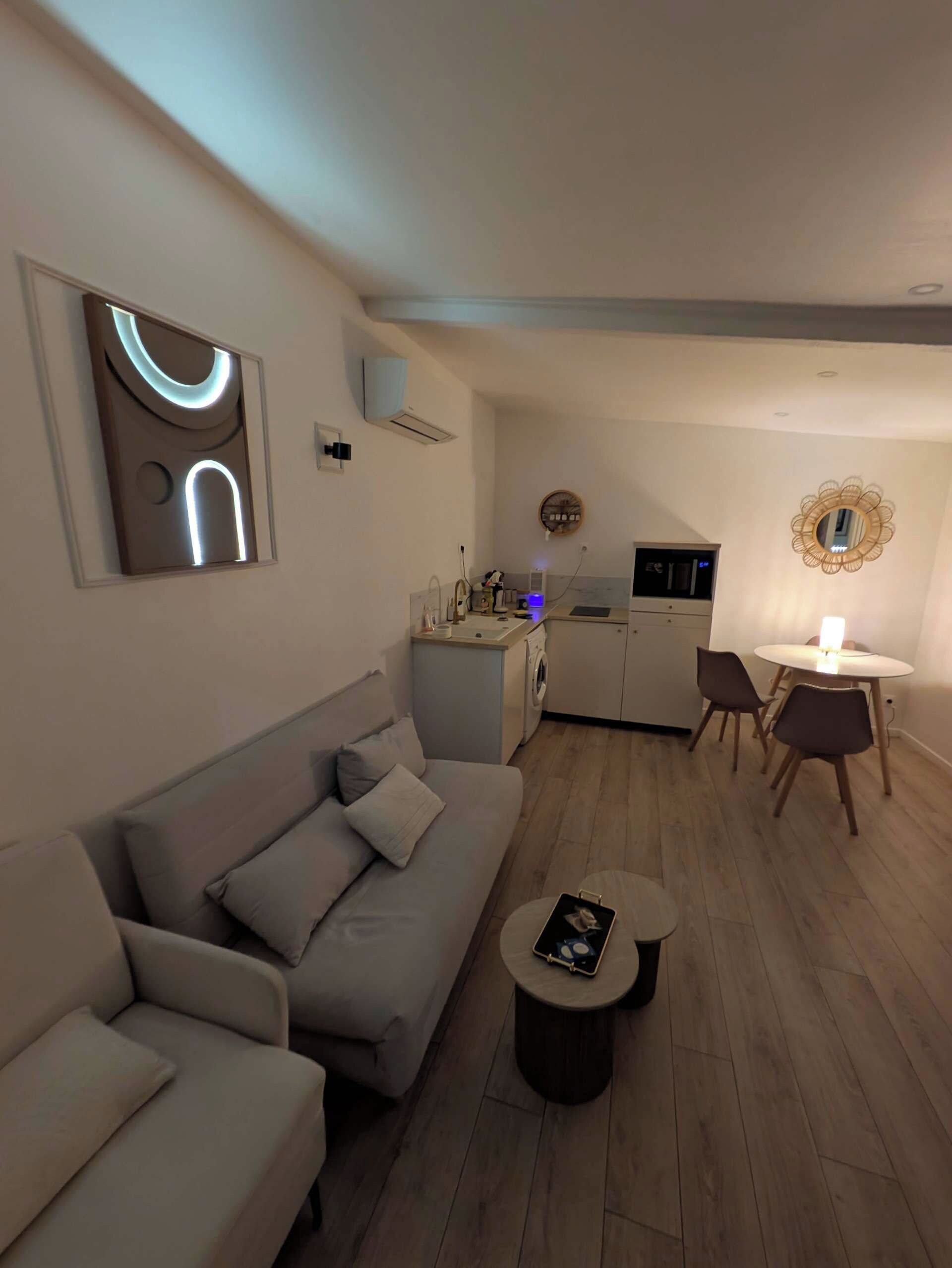 A modern living room with a sofa, a coffee table, and a dining area with chairs and a table.