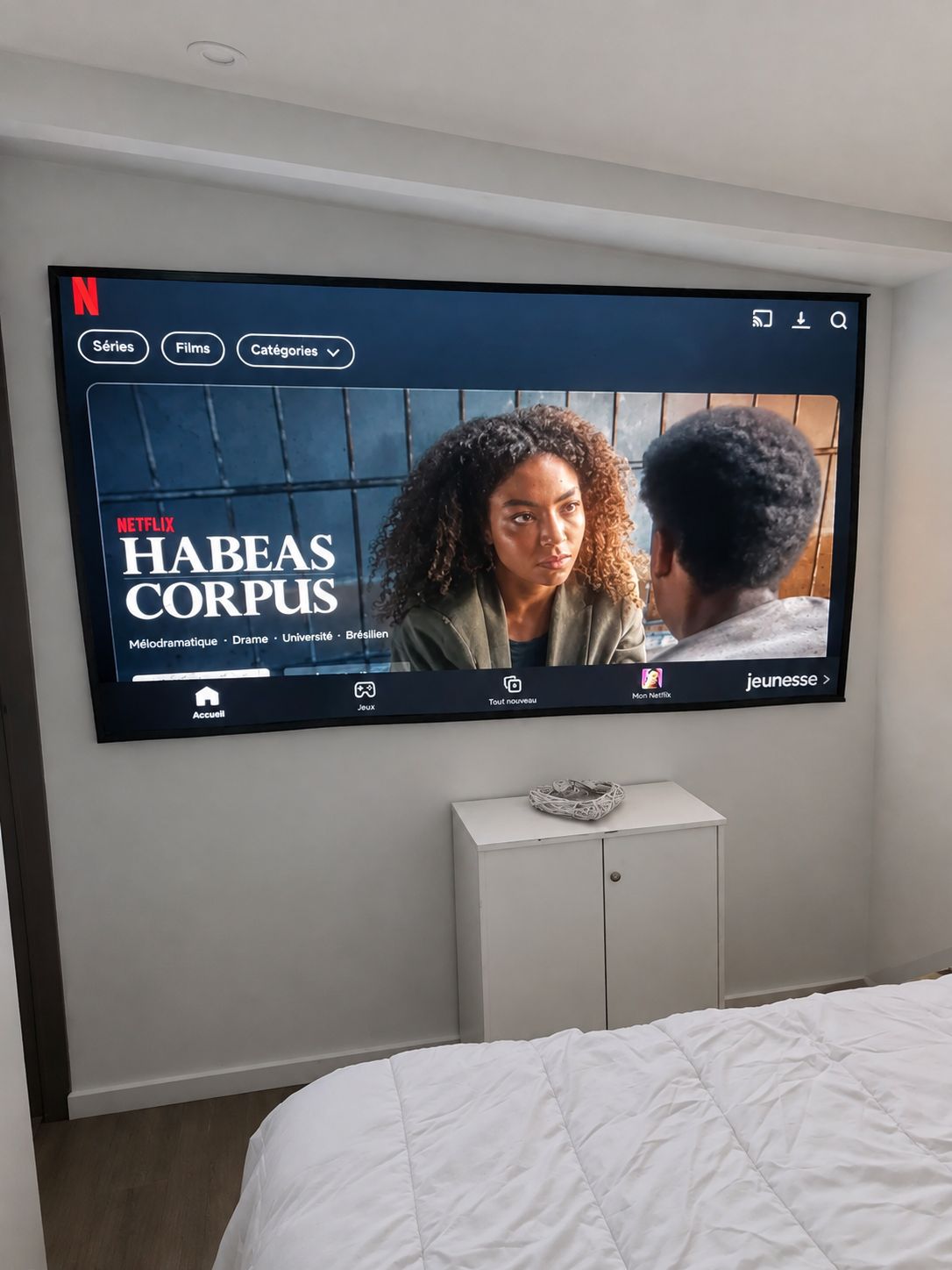 A television mounted on a wall displaying the Netflix series 'Habeas Corpus.'