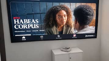A television mounted on a wall displaying the Netflix series 'Habeas Corpus.'