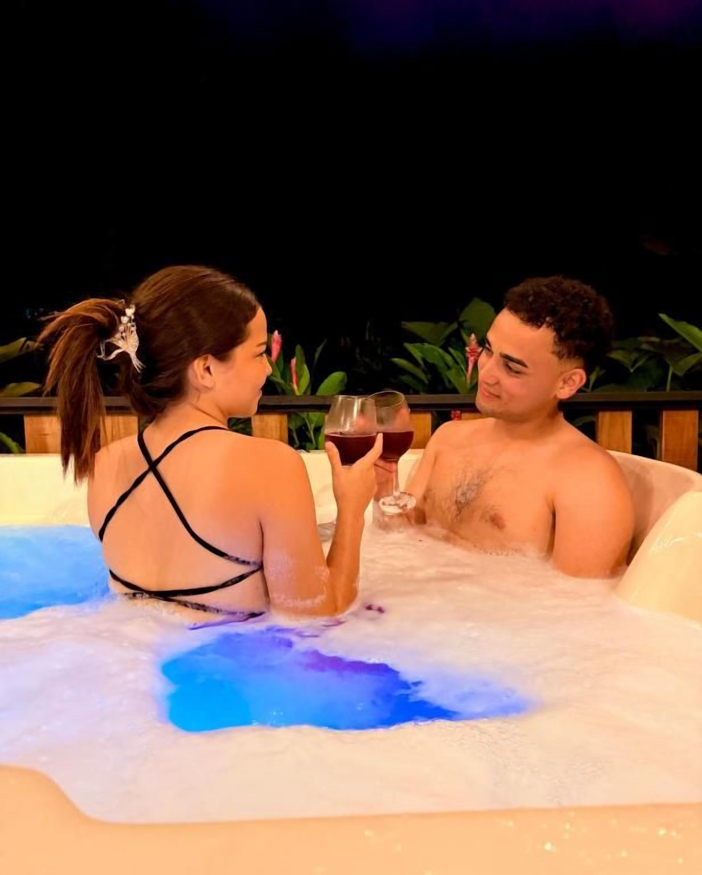 Two individuals in a hot tub with a dark background.