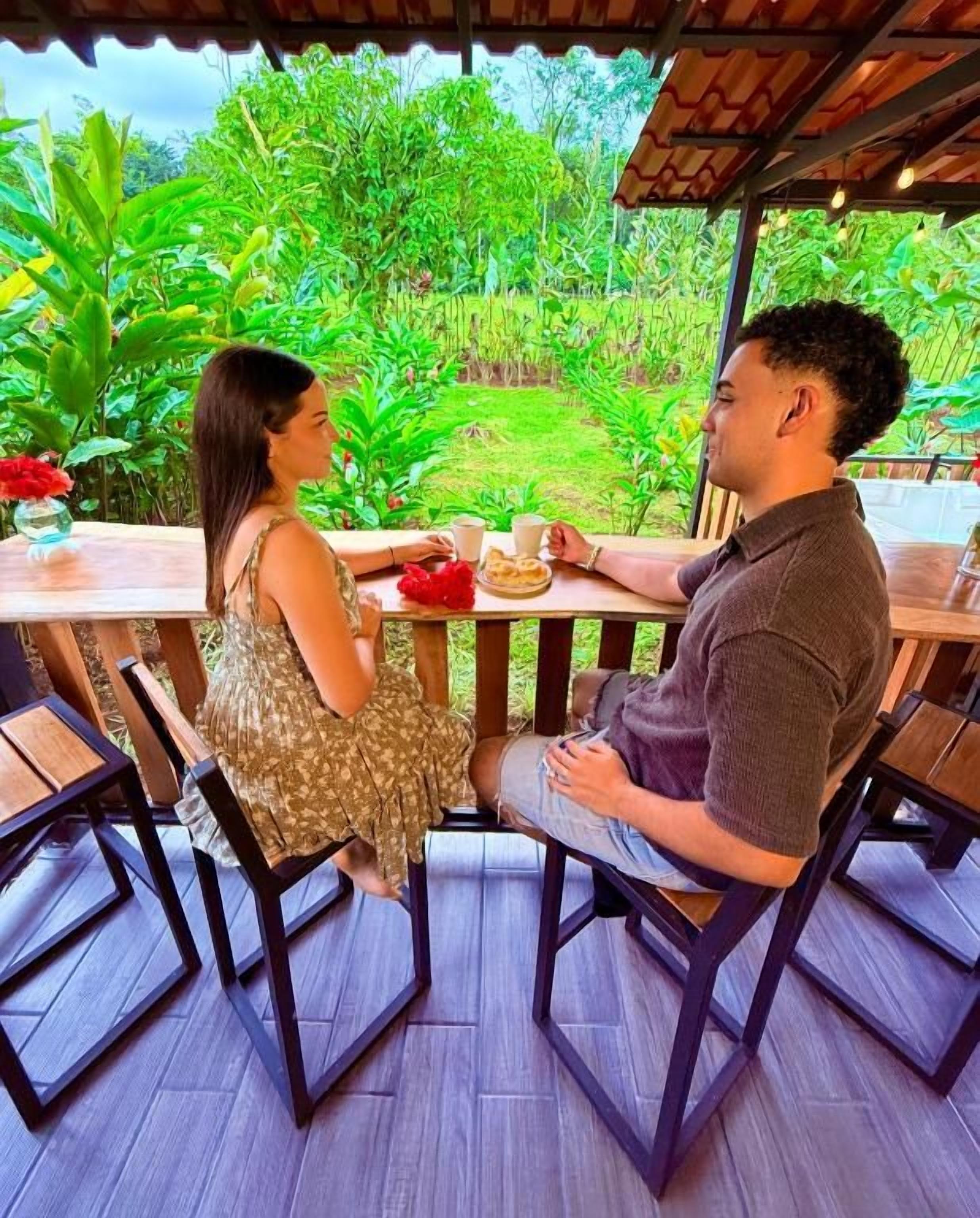 A couple seated at an outdoor table with a view of a lush garden.