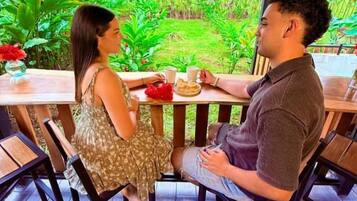 A couple seated at an outdoor table with a view of a lush garden.