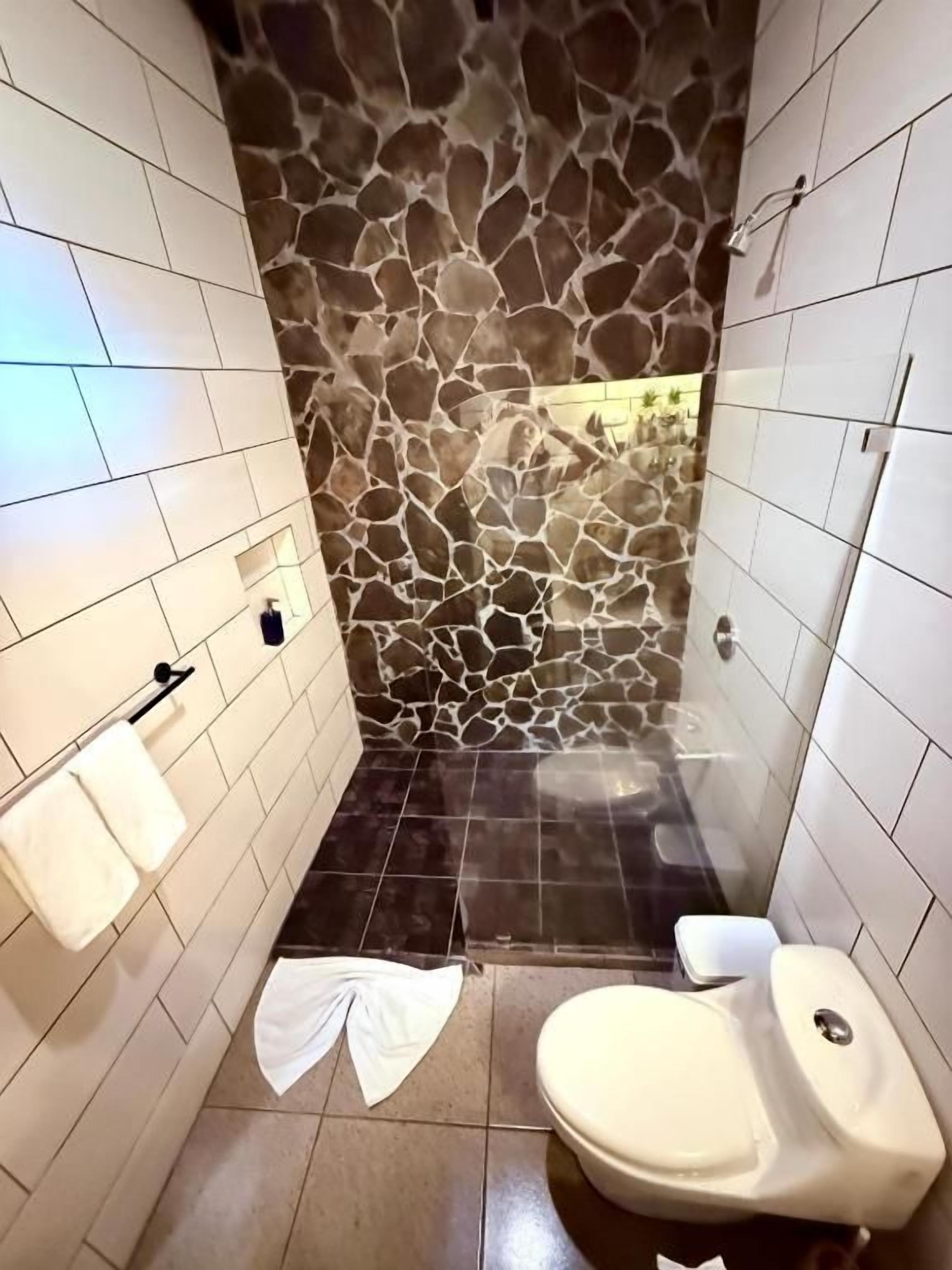 A bathroom with a stone wall, a toilet, and a towel rack.
