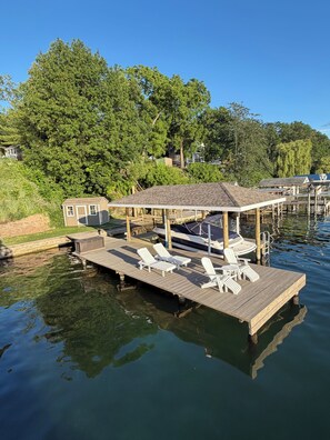A wooden dock with lounge chairs and a covered pavilion by a calm body of water. - Wolf Den Private Suite and Dock (Hector)