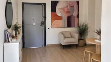Una habitación moderna con puerta cerrada, un sofá, una mesa de comedor con sillas y un cuadro abstracto grande en la pared.