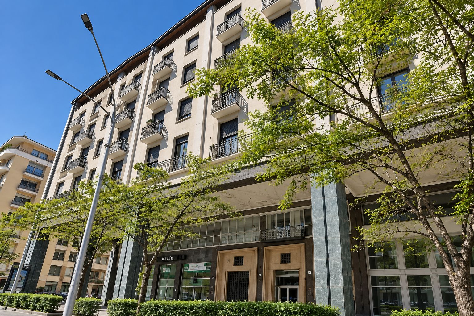 Un edificio de varios pisos con balcones, entrada a nivel de suelo y cielo despejado.