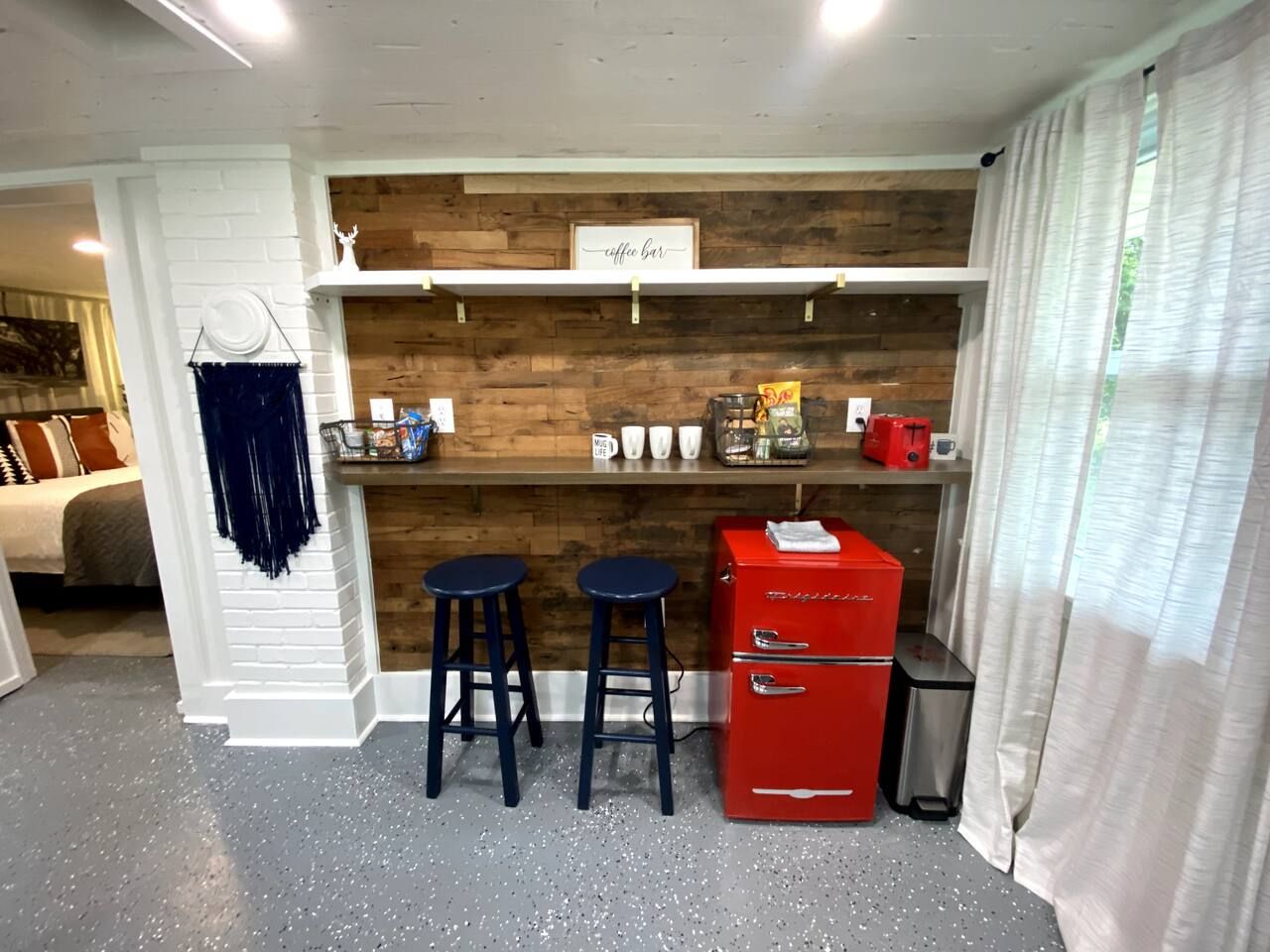 A compact kitchen area with a wooden wall, a coffee bar, and a red appliance.