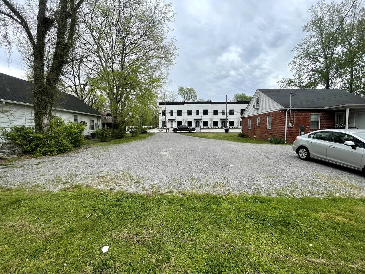 Un quartier résidentiel avec une allée de gravier menant à un bâtiment blanc doté de nombreuses fenêtres.