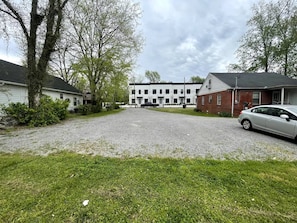 Un quartier résidentiel avec une allée de gravier menant à un bâtiment blanc doté de nombreuses fenêtres.