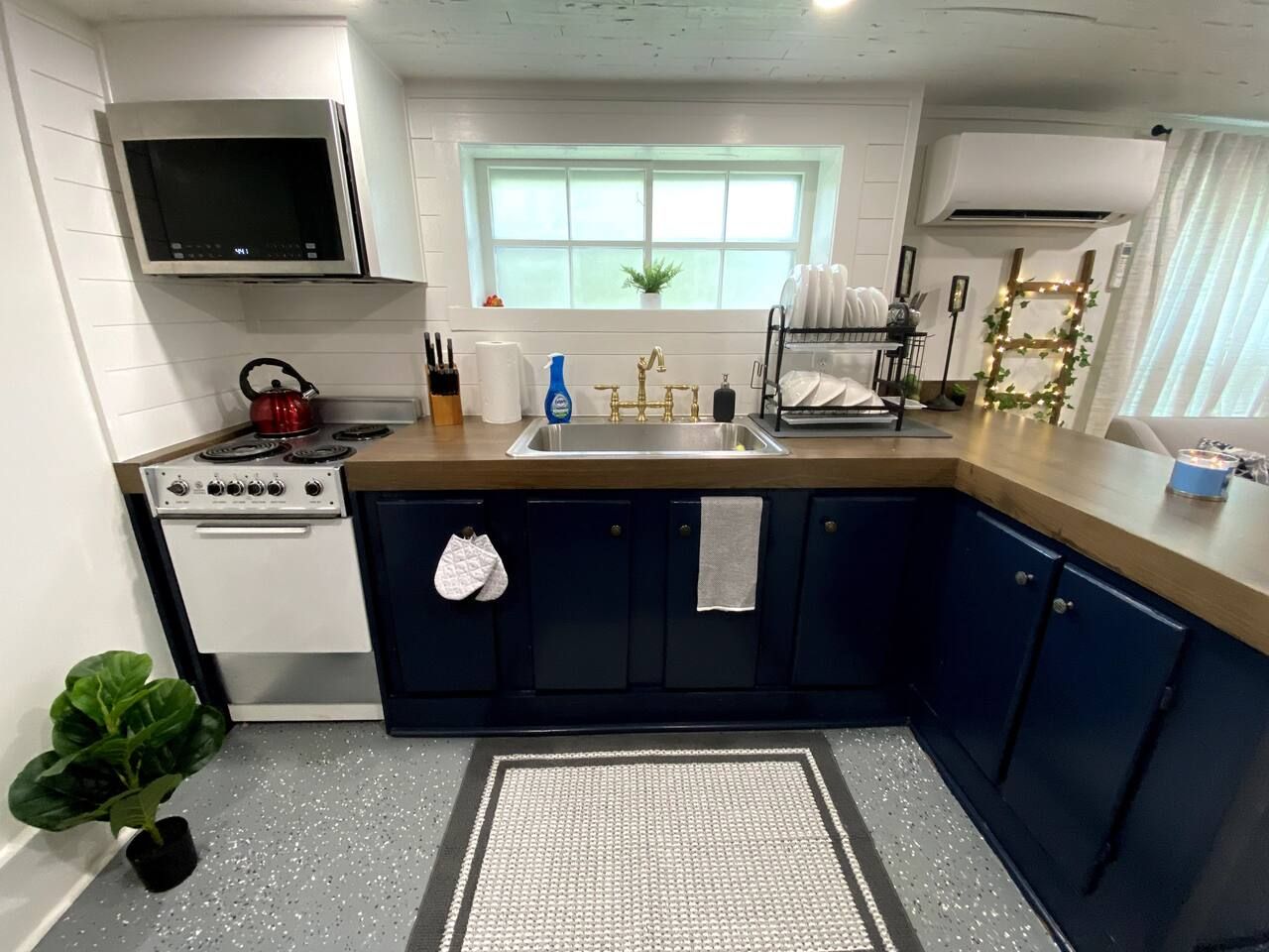 A kitchen with a stove, sink, cabinets, and a window.