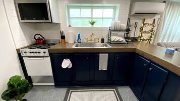 A kitchen with a stove, sink, cabinets, and a window.