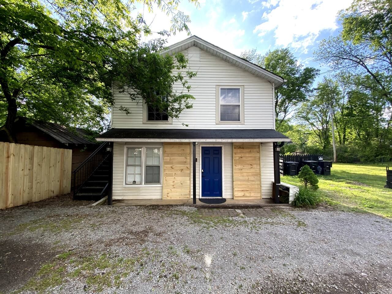 A two-story house with a front porch, a visible staircase, and a blue door.