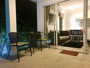Ein Balkon mit einem Stuhl, einem Sofa und einem kleinen Tisch.