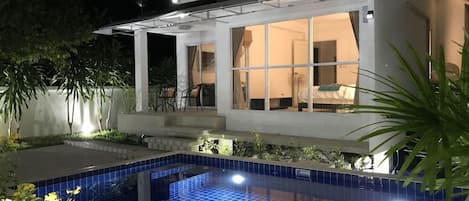 Une maison moderne dotée d’une piscine, d’un patio couvert et d’une chambre visible de l’extérieur.