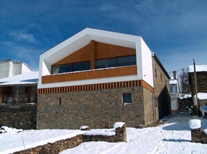 A modern two-story building with a stone facade and a large window on the upper floor.