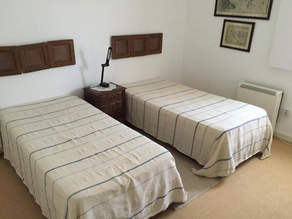 A room with two single beds, a bedside table with a lamp, and a radiator.