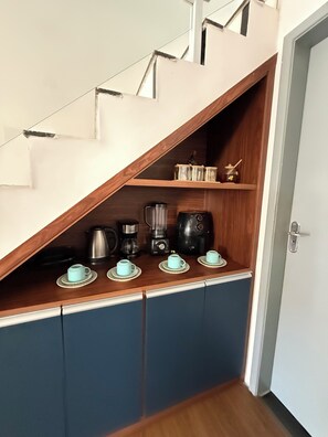 Eine Küche mit einer Holzauskleidung, einer Kaffeemaschine, einem Mixer und einem Wasserkocher.