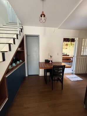 Eine moderne Küche mit einer Holztreppe, einem Essbereich mit Tisch und Stühlen sowie Blick auf die Terrasse.