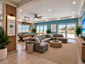 Una sala de estar moderna con mesa de billar, asientos cómodos y grandes ventanales con vista a la playa.