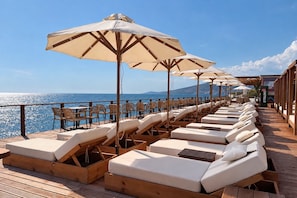 Une terrasse avec des chaises longues et des parasols, offrant une vue sur la mer.
