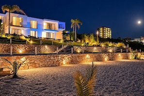 A modern building with multiple windows and a stone retaining wall. - New Listing (Saranda)