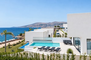 Ein modernes Resort mit Pool, Liegestühlen und Meerblick.