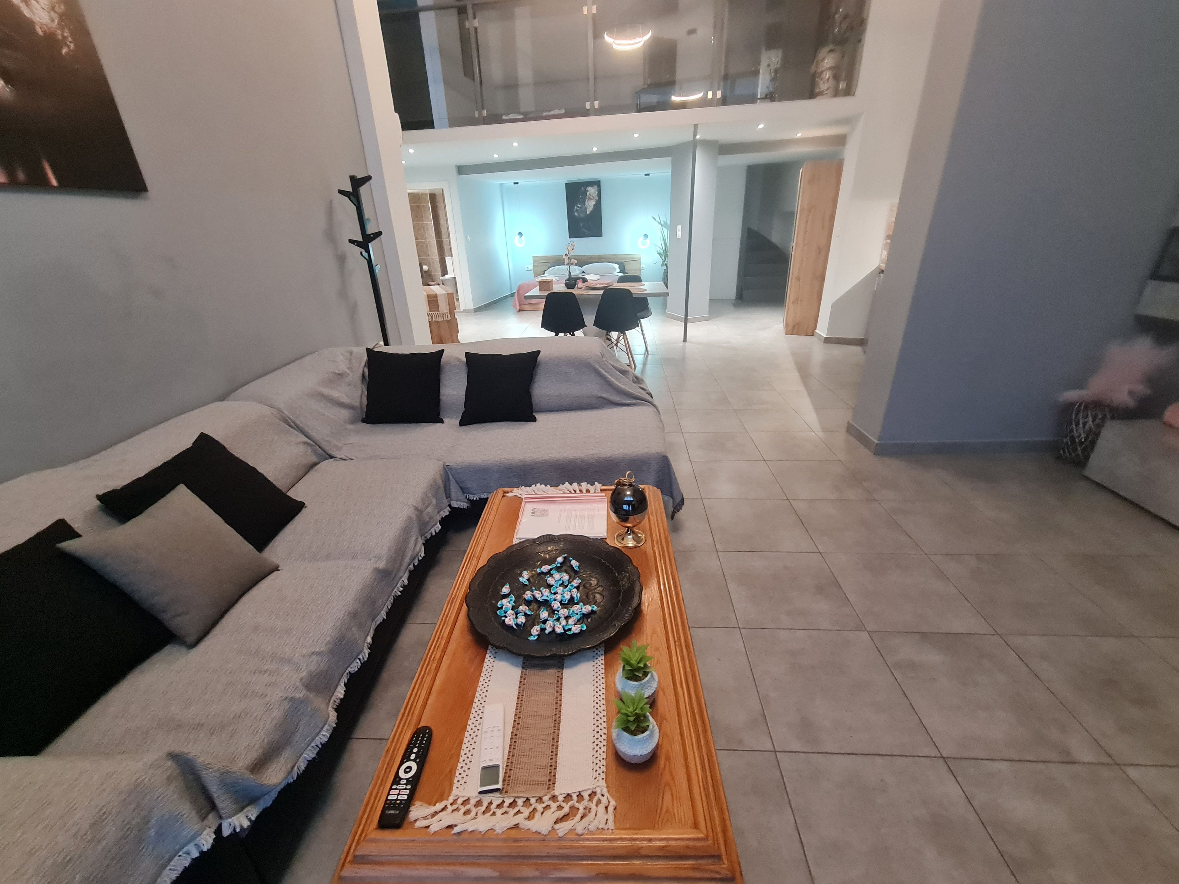 A modern living room with a sectional sofa, a coffee table with decorative items, and a view into the dining area.