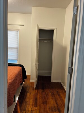 Ein Zimmer mit einem Bett, einem Schrank und einem Fenster mit Jalousien.