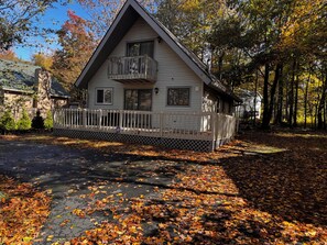 A two-story house with a balcony, surrounded by trees and fallen leaves. - Cozy 3-bedroom house in enchanting Tobyhanna for your getaway (Tobyhanna)