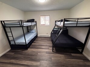 A room with two bunk beds, a window with blinds, and a wooden floor. - Cozy 3-bedroom house in enchanting Tobyhanna for your getaway (Tobyhanna)
