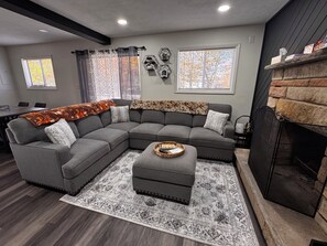 A modern living room with a sectional sofa, ottoman, and patterned rug. - Cozy 3-bedroom house in enchanting Tobyhanna for your getaway (Tobyhanna)