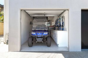 A garage with a blue vehicle parked inside. - Ocean View Balcony King Suite Golf Cart and AC (Oceanside)