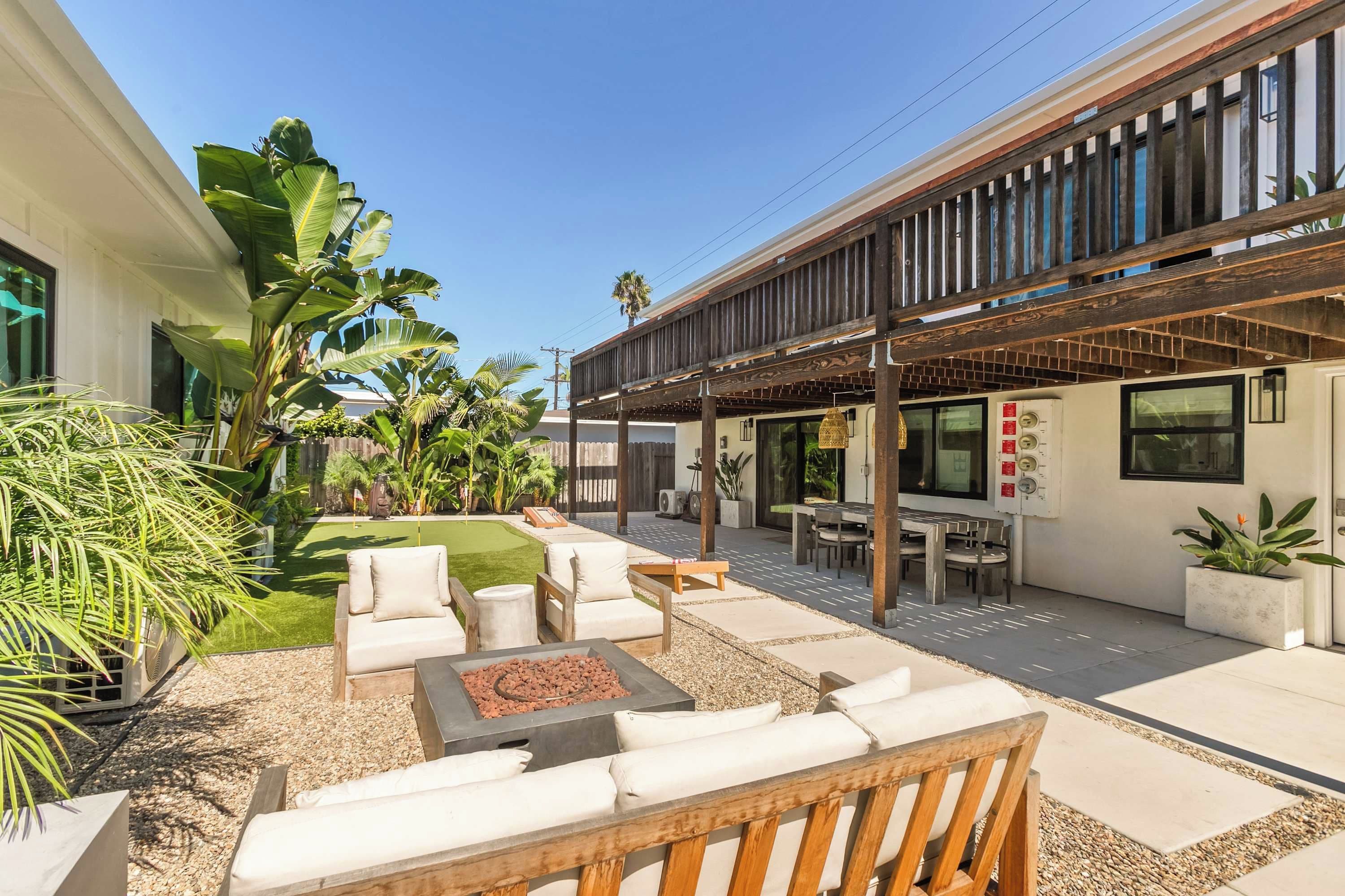 A modern outdoor patio with seating, a fire pit, and a covered area with a pergola.