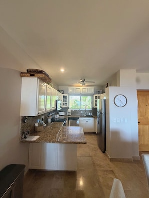 A modern kitchen with white cabinetry, granite countertops, and a built-in island. - Luxury Cabo Condo with Ocean Views Overlooking Cabo Real Golf Course (San José del Cabo)