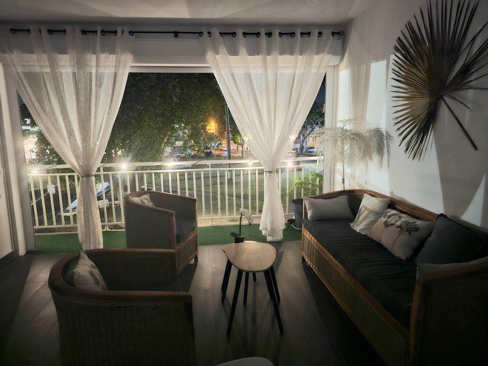 A balcony with a wicker chair, a small table, and a sofa.