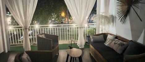 A balcony with a wicker chair, a small table, and a sofa.