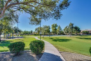 A well-maintained park with a paved walkway, green lawns, and playground equipment. - Soothing 3-bedroom house with AC in charming Peoria (Peoria)