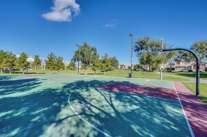 An outdoor basketball court with a green and red surface, surrounded by trees and residential buildings. - Soothing 3-bedroom house with AC in charming Peoria (Peoria)