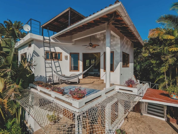 A two-story house with a balcony, a hammock, and potted plants. - Villa Catalina: San Pancho 5BR Estate w/ Pool, Ocean Views, Sleeps 10 (San Francisco)