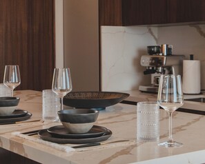 Eine moderne Küche mit Marmorarbeitsplatte, einer Kaffeemaschine und einem Essbereich mit Tisch für zwei Personen.